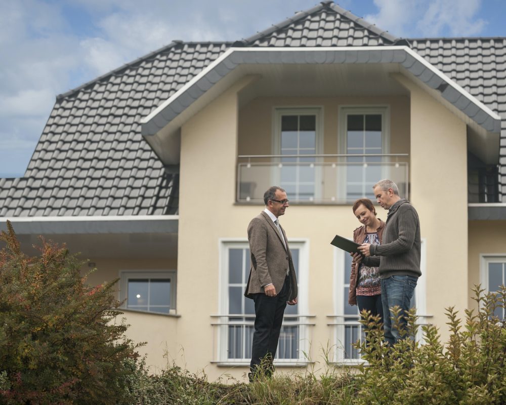 Estate agent with potential buyers in front of residential house